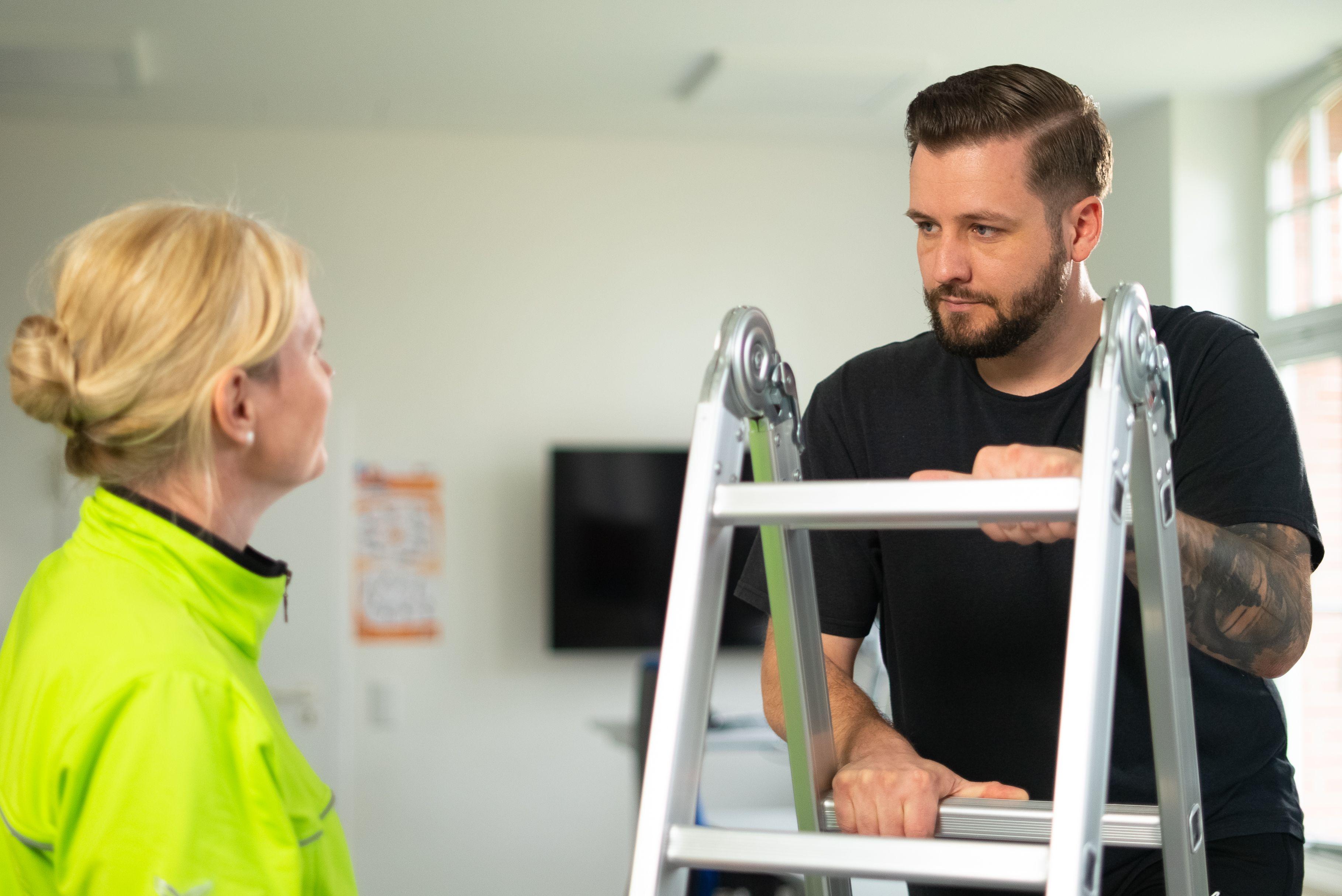 Rehabilitant trainiert gemeinsam mit Physiotherapeutin an einer Leiter.