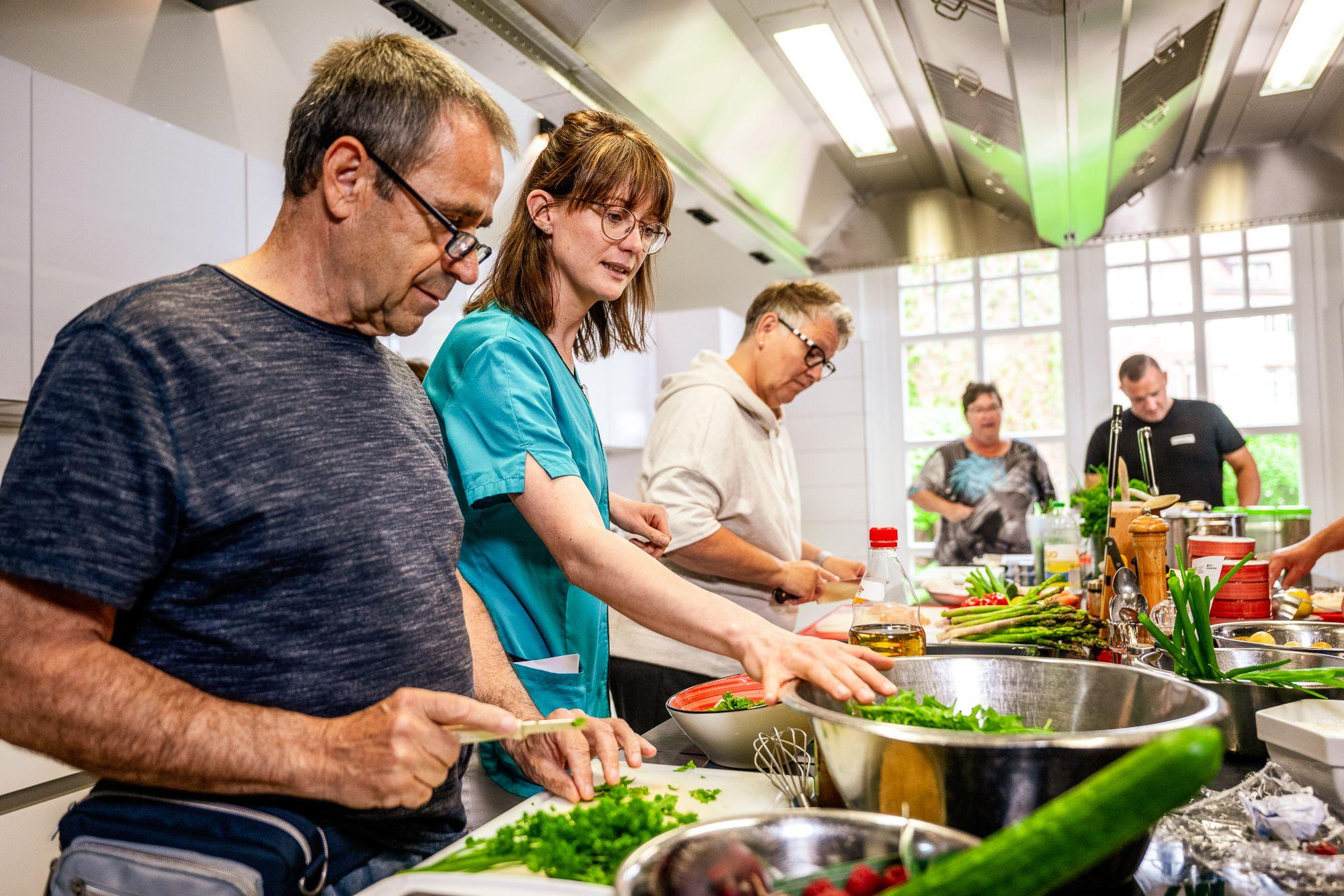 Mehrere Personen bereiten ein Essen in der Lehrküche zu 